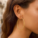 55mm Hoop Earrings 2mm Thickness 14k Yellow Gold model wearing 55mm Hoop Earrings 2mm Thickness 14k Yellow Gold model wearing